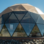 Front view of Heart Mountain lodging dome, glass windows facing mountains and mountains in the background, blue sky